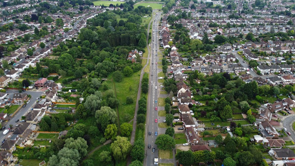 An aerial view of Addiscombe Railway Park and the surrounding residential neighborhood showing a blend of lush green trees and well-maintained gardens. The park features a dense cluster of mature tree